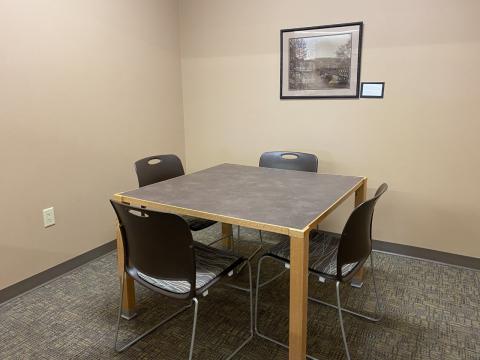 This photo shows a small room with a square table and 4 chairs around it. 