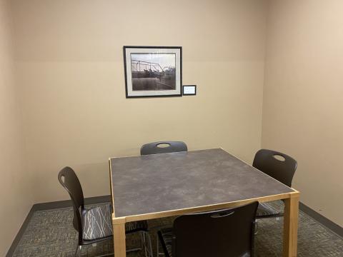 This photo shows a small room with a square table and 4 chairs around it.